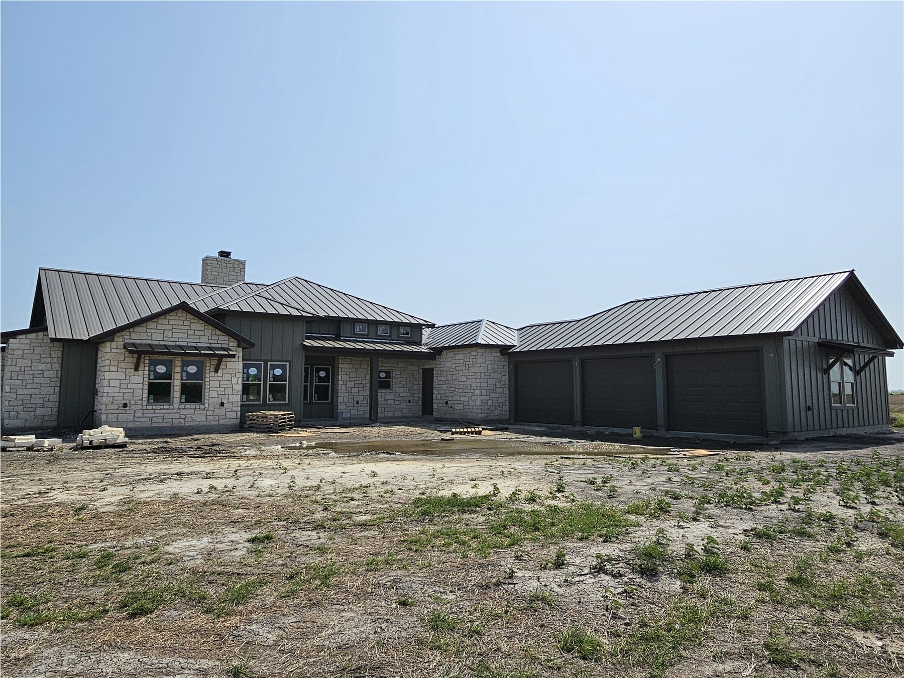 Large stone home with a dark bronze standing-seam metal roof