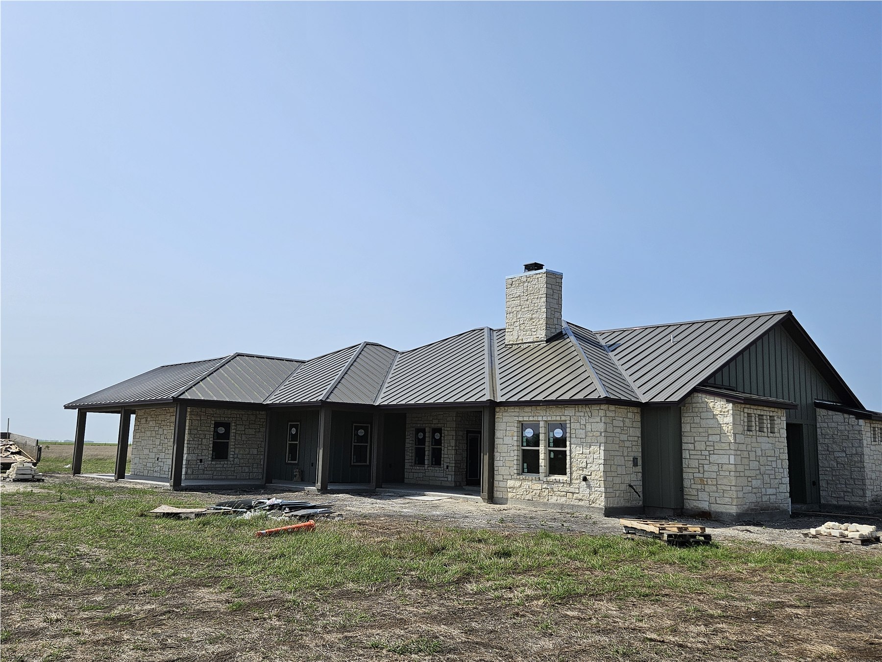 Dark bronze standing-seam metal roof on a large stone home